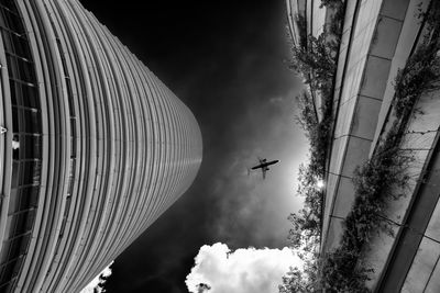 Low angle view of airplane flying against cloudy sky