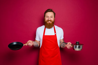 Portrait of man holding red wine against colored background