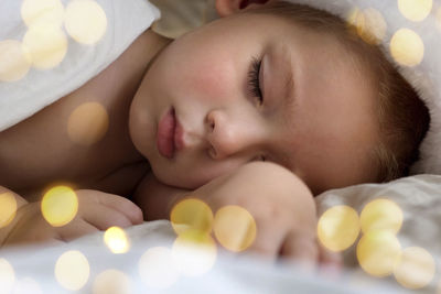 Cute sleeping young boy in santa claus hat. christmas light. winter holiday. toddler baby christmas.