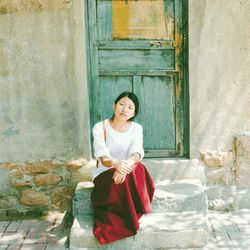 Smiling young woman sitting against brick wall