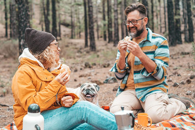 Smiling couple eating food in forest