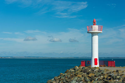 Lighthouse by sea against sky