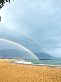 Scenic view of rainbow over sea against sky