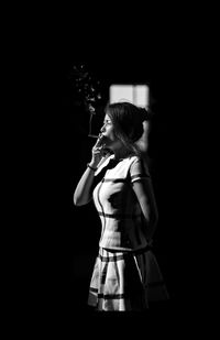 Woman standing against black background