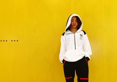 Woman standing against yellow wall