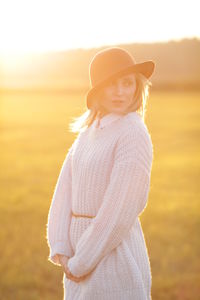 Close-up of young woman standing on grass field during sunset