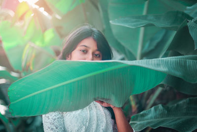 Portrait of beautiful young woman by plants