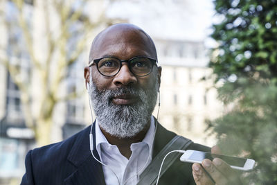 Mature businessman talking on the phone, wearing earphones on the move