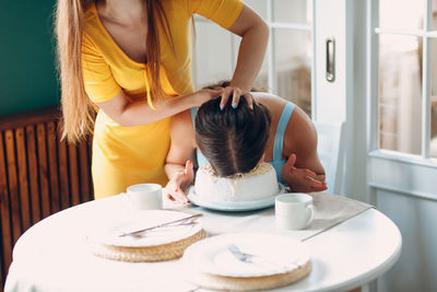 Rear view of mother and daughter on table at home