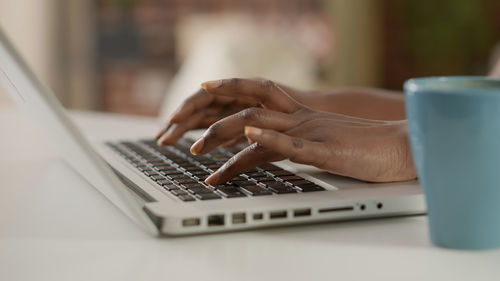 Cropped hands using laptop on table