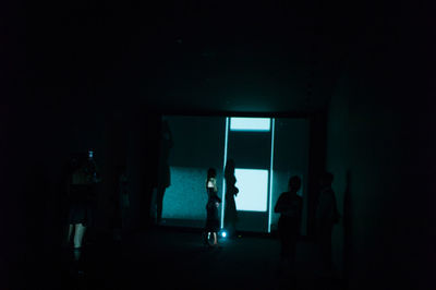 Silhouette people standing in dark room