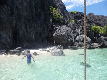 People standing on rock formation in sea