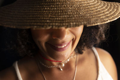 Close-up portrait of a woman wearing a hat against a black background. 