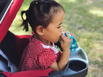 Close-up of girl sitting in baby stroller outdoors