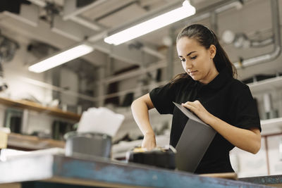 Young working on sheet metal at table in workshop