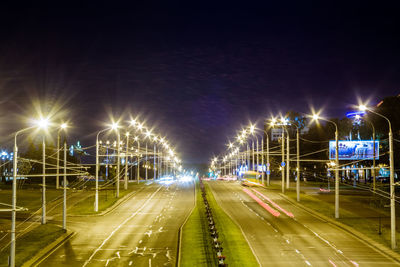Illuminated street lights on road in city at night