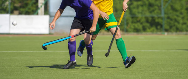 Low section of men playing hockey on turf