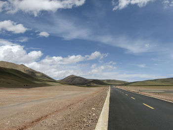 A flat, straight, unmanned asphalt road leads to the front