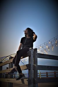 Low angle view of woman against clear sky during sunset