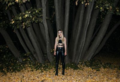 Portrait of young woman standing against trees in forest