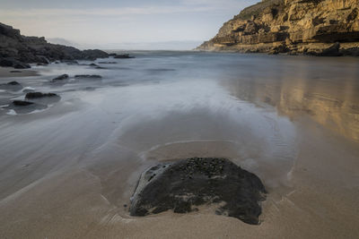 Rock formation on beach against sky