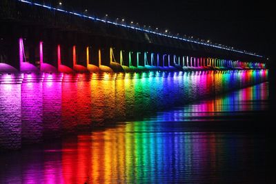 Colorful illuminated bridge over river at night