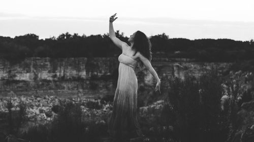 Full length of young woman dancing on field against rock formations