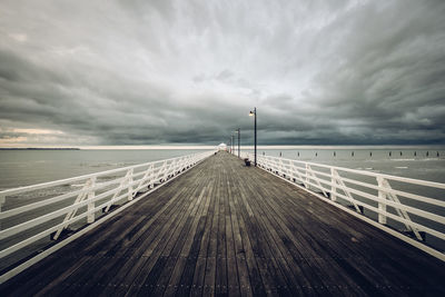 Pier over sea against cloudy sky