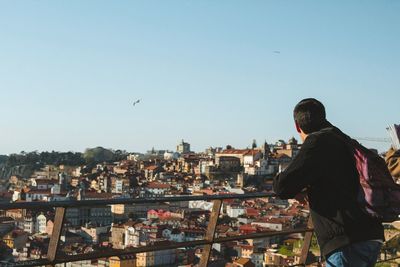 Rear view of woman standing by buildings against sky