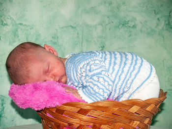 Baby girl sleeping in wicker basket at home
