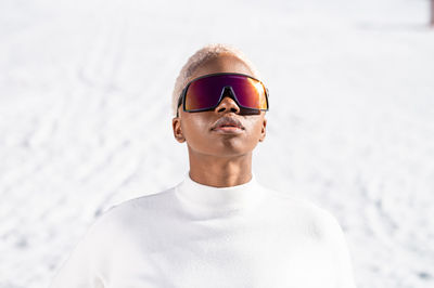 A young african american woman wearing sunglasses having fun in the snow on a winter day