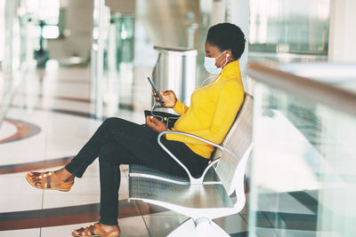 Man using mobile phone while sitting in glass