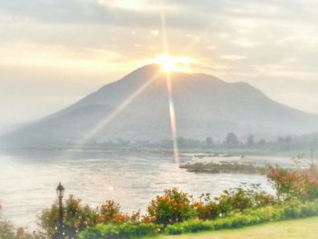 Sun shining through clouds over mountain