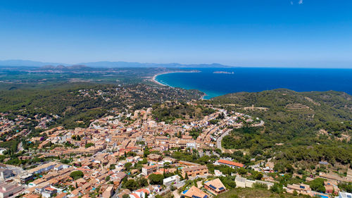 High angle view of townscape by sea against blue sky