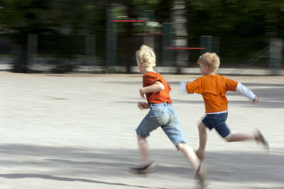 Full length of siblings running on road