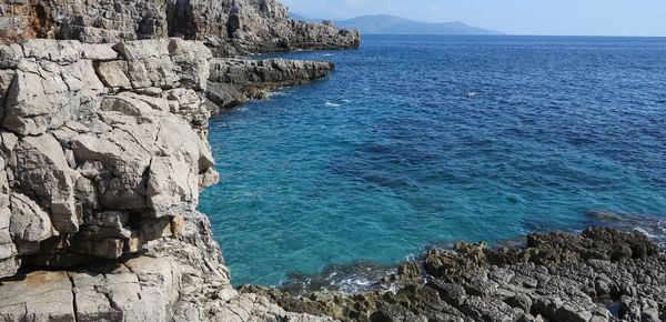 Scenic view of sea by cliff against sky