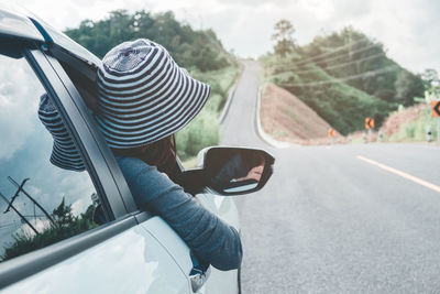 Rear view of woman traveling in car on road