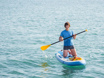 Handsome sportsman on knees paddling on stand up paddleboard. sup surfing. active lifestyle. 