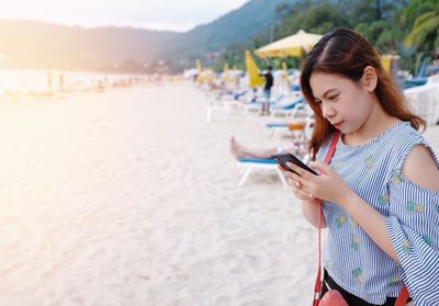 Young woman using mobile phone at beach