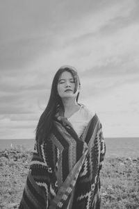 Woman standing at beach against sky in black and white