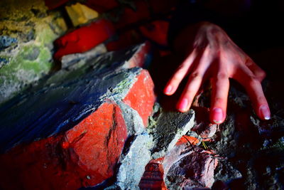 Cropped hand touching rock formation