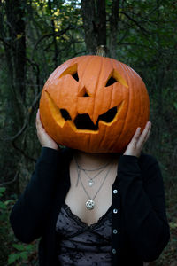 Midsection of person with pumpkin on plant during halloween