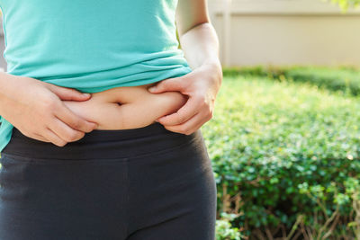 Midsection of woman sitting by plant