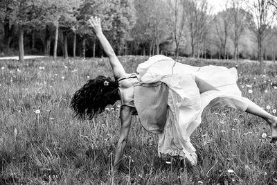 Rear view of woman doing cartwheel on grassy field