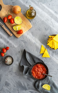 Tomato dip with with nachos tortillas and main ingredients on grey background. flat lay