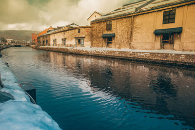 Buildings by river against sky