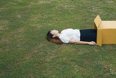Rear view of woman lying on grass in field