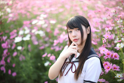 Portrait of woman standing by pink flowering plants