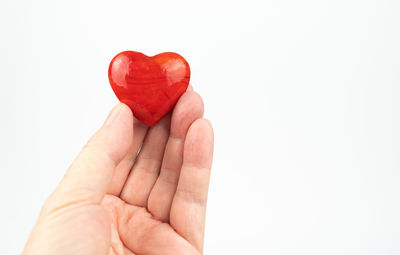 Close-up of hand holding heart shape against white background