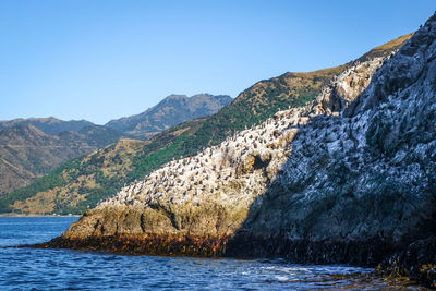 Scenic view of sea and mountains against clear sky